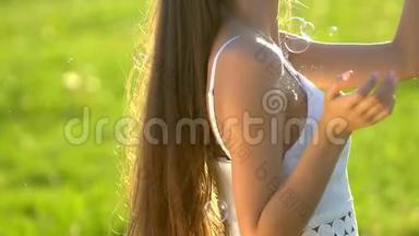 长发美女吹泡泡香皂在绿草公园自然。户外快乐美女。青少年